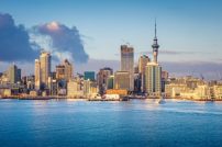 Auckland, New Zealand skyline Auckland, New Zealand - August 14 2024_ Aerial drone view of a ferry that leaves the Auckland historic ferry terminal with the skyline and a massive car carrier in New Zealand largest city