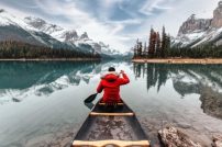Male traveler in winter coat canoeing in Spirit Island on Maligne Lake at Jasper national park, AB, Canada Male traveler in winter coat canoeing in Spirit Island on Maligne Lake at Jasper national park, AB, Canada